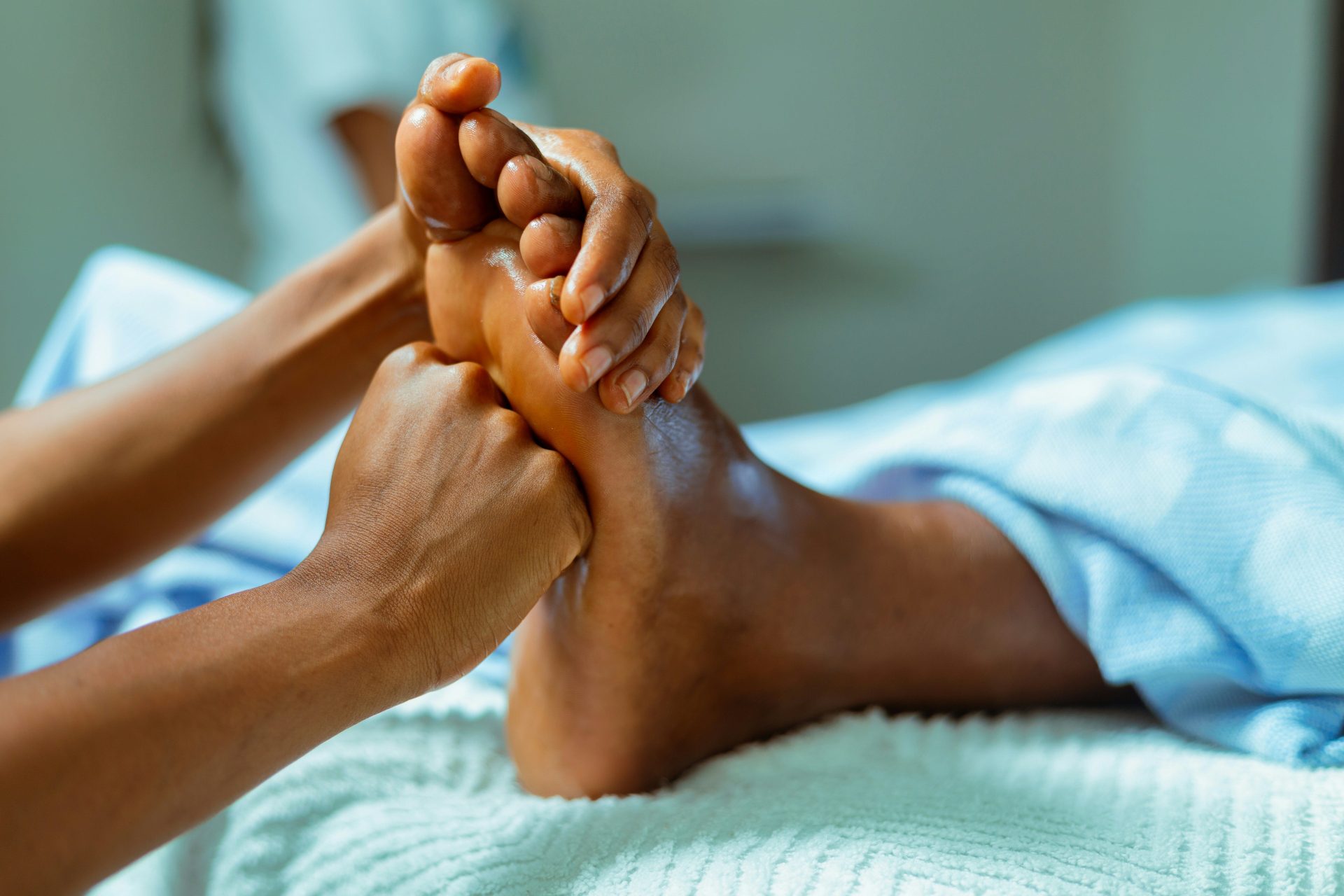 Hands massaging a foot with oil on a white towel