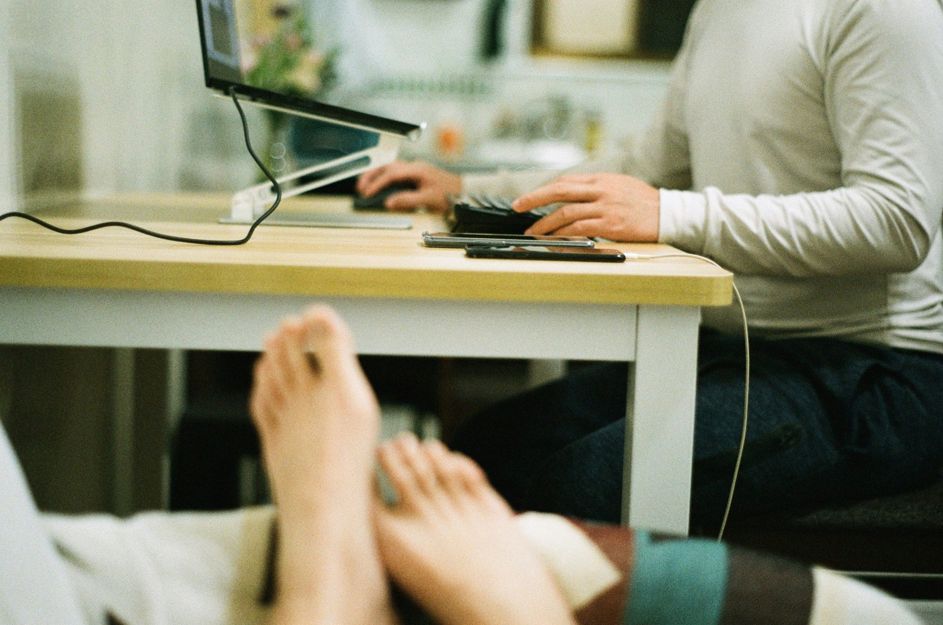 a person sitting at a table with a laptop and a cell phone